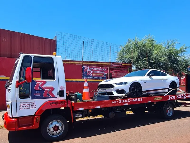 Guincho da RR transportando carro esportivo branco em frente à empresa